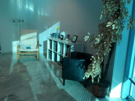 Espacio de lectura y relajación con sillas y estanterías en la consulta de psicología.